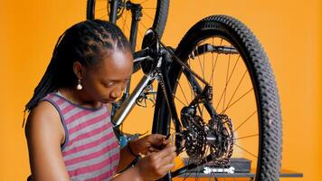 Specialist using screwdriver and hex socket wrench to secure wheel on bicycle in studio background repair shop. Technician screwing bolts on bike parts, fixing rear derailleur, camera B photo