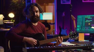 retrato de artista grabación melodías en grajilla software con su guitarra, disfrutando hora en su hogar estudio oficina. audio ingeniero y músico creando nuevo pistas, estéreo electrónico instrumentos cámara una. foto