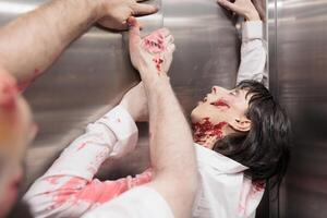 Walking dead creatures stuck in office elevator, trying to escape to infect more people and eat brains. Terrifying bloody cadavers trapped in escalator, pulling on metallic doors photo