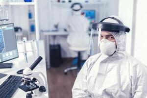 cansado químico ingeniero en proteccion traje en contra infección con covid19 mirando a camara.sobretrabajada investigador vestido en protector traje en contra invección con coronavirus durante global epidemia. foto