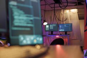 Computer screens with malware running code stealing sensitive information in hackers abandoned warehouse. Malicious software with internet virus on monitors in dark hideout with neon light photo