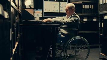 Paralyzed senior inspector reviewing classified case records in incident room, gathering intelligence for private investigation. Wheelchair user with limited mobility accessing databases. Camera B. photo
