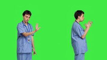 Displeased irritated nurse shouting no and arguing with someone against greenscreen backdrop, showing rage and anger while she wears hospital scrubs. Aggressive medical assistant. Camera B. photo