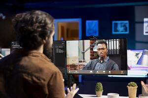 IT specialist working from home in videocall with coworker, testing and deploying programs and systems. Programmer checking code with colleague in teleconference, sitting at desk chair in apartment photo