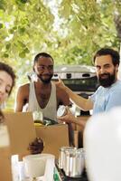 Less fortunate african american man receives canned goods and donation box from caucasian male volunteer. Image showcasing charitable effort aimed to alleviate poverty and hunger within the community. photo