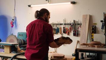 Carpenter selecting tool from rack to use on wood materials, helped by african american coworker. Craftsperson doing quality assurance on lumber pieces pile with BIPOC apprentice, camera A photo