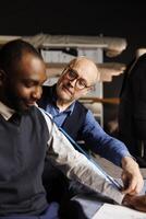 Businessman getting arm measurements taken by precise senior suitmaker in atelier shop. Skilled elderly tailor sizing up customer proportions for handmade bespoke office suit comission photo