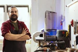 retrato de optimista carpintería profesional preparando a comienzo producción en sucio mueble montaje tienda. alegre artesano en estudio a banco de trabajo Listo a cortar madera piezas foto