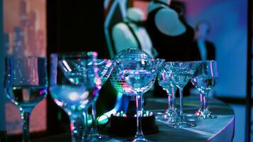 Empty club with alcohol in glasses, discotheque with stage lights and music at nightclub. Alcoholic drinks prepared for disco party and clubbing, live show. Close up. Handheld shot. photo