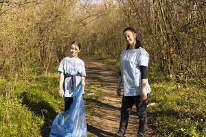 orgulloso madre y hija trabajar como voluntario a lucha contaminación, restaurar natural ambiente y Ayudar con ilegal dumping. pequeño niño reciclaje el plastico residuos en un disposición bolsa. foto