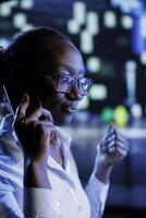 African american woman strolling around cityscape at night, enjoying conversation over the phone with best friend. Citizen walking home from work, making telephone calls to make commute more enjoyable photo