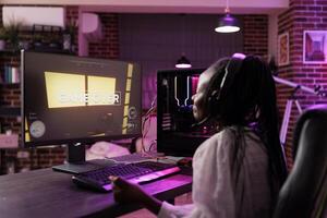 Content creator playing online multiplayer game on gaming PC, losing in live esports tournament. African american pro gamer defeated while streaming game for audience watching from home photo