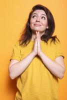 casual caucásico dama sin esperanza mirando arriba y Orando con palmas cerca juntos en frente de aislado antecedentes. humilde joven mujer siendo religioso teniendo esperanza y fe. foto