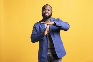 Portrait of assertive man asking for timeout, doing hand gestures, feeling fatigued. Unhappy person doing vehement pause sign gesturing, wishing for break, studio background photo