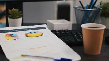 Financial report on desk next to paper cup of coffee in empty office, close up shot. Company files containing economic graphs and pie charts near hot beverage on table in workspace photo