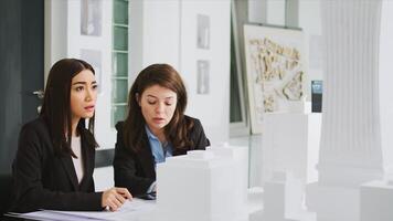 arquitectónico agencia trabajadores tomando notas en planos, calculador real escala mediciones a garantizar el Perfecto elementos para el construcción equipo. mujer desarrolladores estudiando 3d impreso modelo. foto