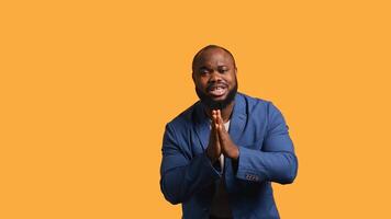 African american man putting hands together in begging gesture, making wish, isolated over yellow studio background. BIPOC person asking for something, praying and hoping, camera B photo