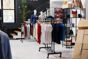 Empty fashion store with casual and formal wear design, retail shop with stylish clothes on hangers and racks. Modern boutique inside of shopping mall, fashionable merchandise on sale. photo