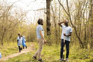 equipo de personas haciendo voluntario trabajo a crecer arboles en el bosque, cubierta agujeros en el suelo con más vegetación para repoblación forestal. contribuyendo a naturaleza conservación misión. foto