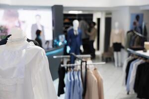 Formal apparel showcasing closeup in empty clothing store with blurred background. Stylish blouses and shirts on hanger and mannequin in shopping center with no people indoors photo