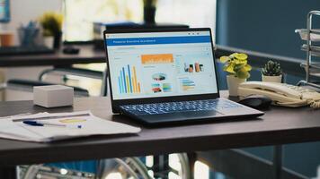 Inclusive office with wheelchair in blurry background and notebook in foreground showing marketing report. Workspace offering accessibility for workers and laptop with business analytics, panning shot photo