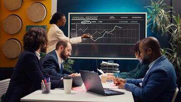 Startup team reviewing annual reports infographics on interactive board, studying market entry approaches and demands to facilitate global growth. Business employees accomplish goals. Camera B. photo