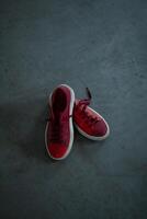 rojo brillante zapatillas en un gris hormigón piso foto