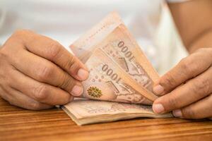 Asian business woman holding Thai banknote currency money. photo