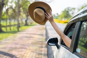 Happy enjoy and freedom in traveling trip with raised hand and holding hat outside of window car in summer vacation holiday. photo