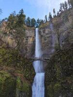 Columbia River Gorge, Oregon, USA - 02.24.2024 Tourists are enjoying a up-close view of roaring Multnomah Falls from Multnomah Creek Bridge. photo