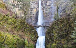 Columbia River Gorge, Oregon, USA - 02.24.2024 Tourists are enjoying a up-close view of roaring Multnomah Falls from Multnomah Creek Bridge. photo