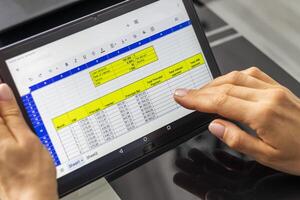 Close up shot of the woman with beautiful hands , using tablet, studying mortgage loan amortization table. Banking photo