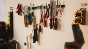 Close up of electric router with woodworking tools on rack in background in workshop. Focus on hand powered equipment in front of chisels, screwdrivers, on wall in carpentry studio, panning shot photo