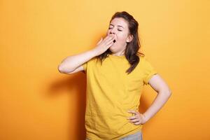 retrato de caucásico mujer bostezando y cubierta su boca, sensación soñoliento en estudio. cansado hembra persona que cae dormido mientras posando y en pie terminado aislado antecedentes. foto