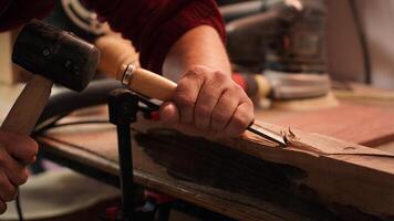 Craftsperson carving into wood using chisel and hammer in carpentry shop with precision. Manufacturer in studio shaping wooden pieces with tools, making wood art, camera A close up shot photo