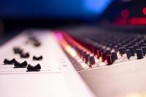 Control room desk with motorized faders and multiple knobs used in processing or editing tracks, post production concept. Panel board having buttons and sliders for recording audio. Close up. photo