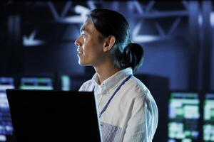 Cheerful BIPOC man between server hub rows providing processing resources for businesses worldwide. Computer scientist fixing data center mainframes tasked with managing massive databases photo