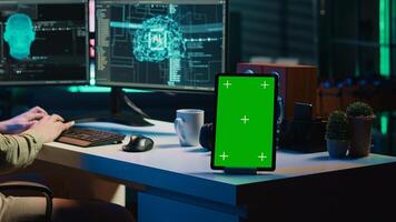 Focus on isolated screen tablet next to programmer updating artificial intelligence, making it become sentient. IT specialist programming self aware AI with chroma key device, camera A photo