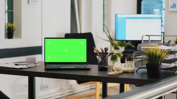 oficina con verde pantalla ordenador portátil y monitor en antecedentes con programado clientela lista. Bosquejo cuaderno en espacio de trabajo y clientes financiero consultas lista en el espalda en monitor foto