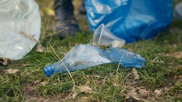 Group of volunteers cleaning the forest from litter and plastic waste, grabbing trash and junk with a long claw tool. Environmental activists picking up rubbish. Close up. Camera A. photo