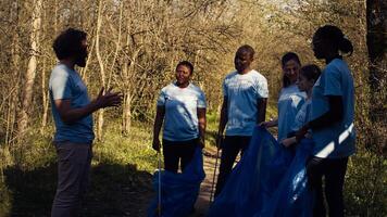 equipo de activistas cosecha arriba el plastico residuos a reciclar y recoger basura, limpieza el bosque natural ambiente para conservación. personas haciendo voluntario trabajo a salvar el planeta. cámara b. foto