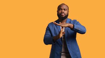 Portrait of assertive BIPOC man asking for timeout, doing hand gestures, feeling fatigued. Unhappy person doing vehement pause sign gesturing, wishing for break, studio background, camera B photo