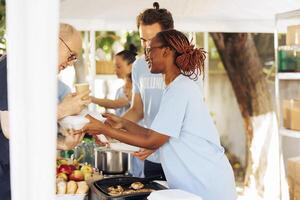 Multiracial hunger relief team provides free meals and assistance at local center, supporting the needy and homeless. Volunteers distribute non-perishable food, sharing compassion and hope. photo