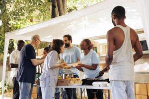 Humanitarian aid group assists in the distribution of contributions to people in need at a homeless and refugee shelter. Volunteers serve meals and provide help through a non-profit food bank. photo