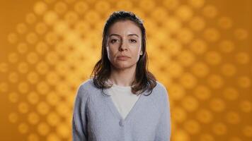 Portrait of relaxed woman posing, looking at camera, isolated over yellow studio background. Caucasian person dressed in casual attire standing, feeling confident, camera B photo