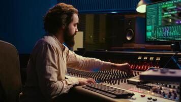 Mixing engineer focuses on blending and balancing individual tunes of a recording to create song, audio editing software in control room. Expert deals with technical aspects of sound. Camera B. photo