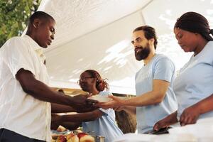 Interracial group in support of hunger relief volunteering in distribution of essential items and free food to needy and less fortunate individuals. Poor and homeless people receive humanitarian aid. photo