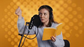 Voice actor looking to producer off camera to know when to start narrating book, producing audiobook. Narrator doing counting on fingers gesturing before starting digital recording of novel, camera B photo