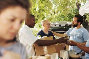 Compassionate group of volunteers providing food to the poor, sharing happiness, and fostering friendship. Outdoor food bank, hunger relief team handing out donation boxes to needy and less fortunate. photo