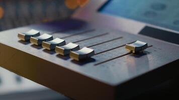 Sound engineer operating on motorized faders controller in professional studio, editing and mixing tracks to create a song. Audio technician works with sliders and soundboard panel. Camera A. photo